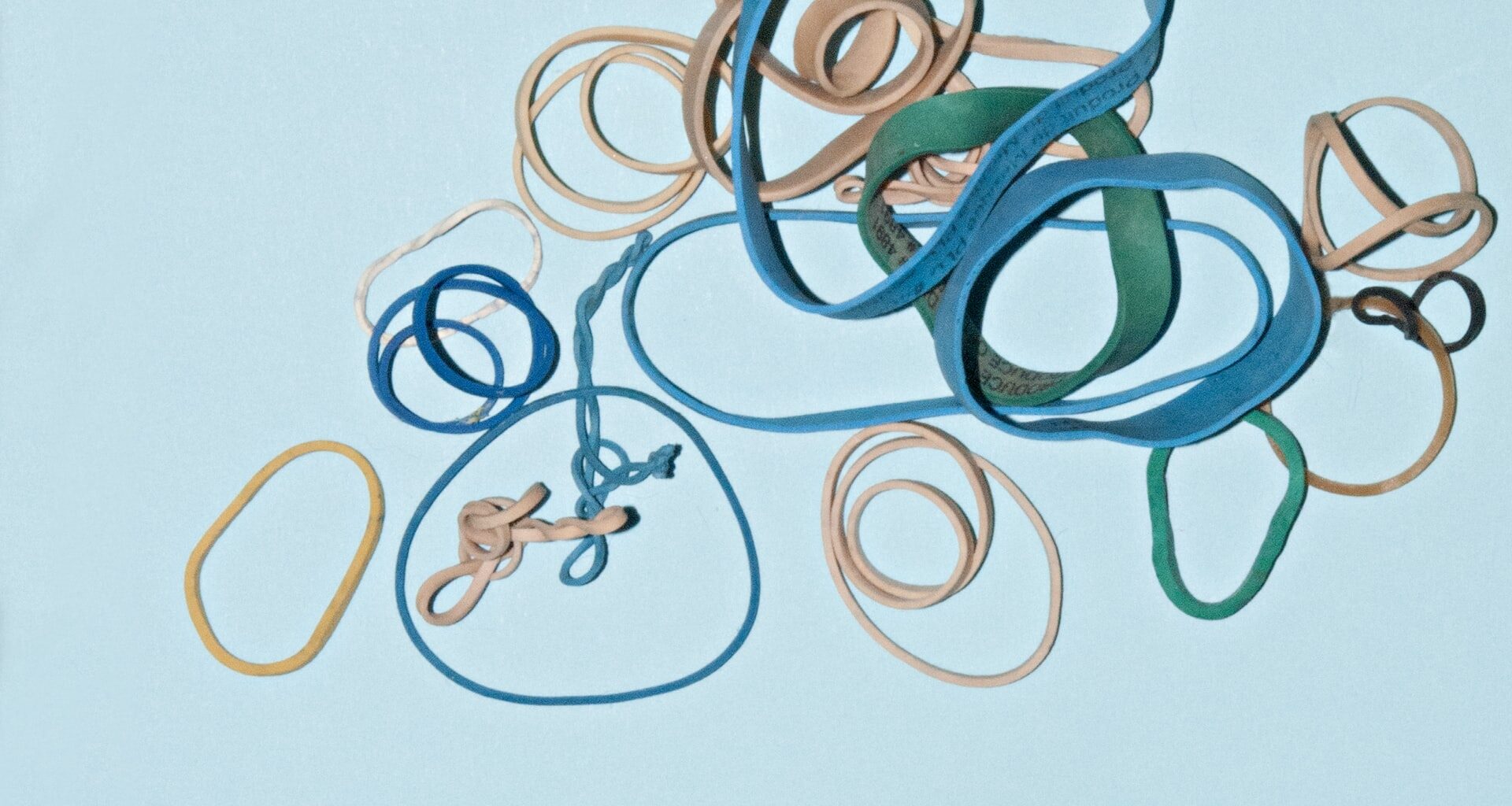 an assortment of rubber bands on a light blue background, all different shapes and sizes