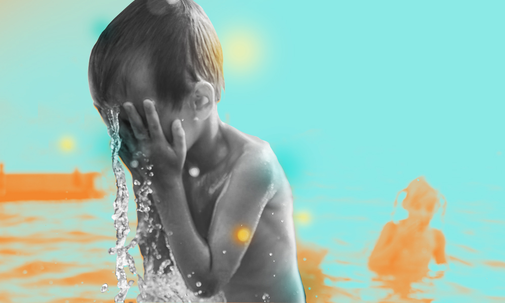 A black-and-white image of a child splashing water on their face, with an orange child in blue water in the background.