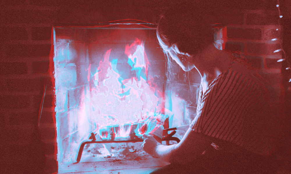 A pink and black silhouette of a person stoking a pink, white, and blue fire in a fireplace.