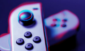 A purple Nintendo Switch left controller rests perpendicularly on top of a purple Nintendo Switch right controller.